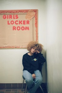 a girl sitting on a chair in front of a sign that says girls locker room